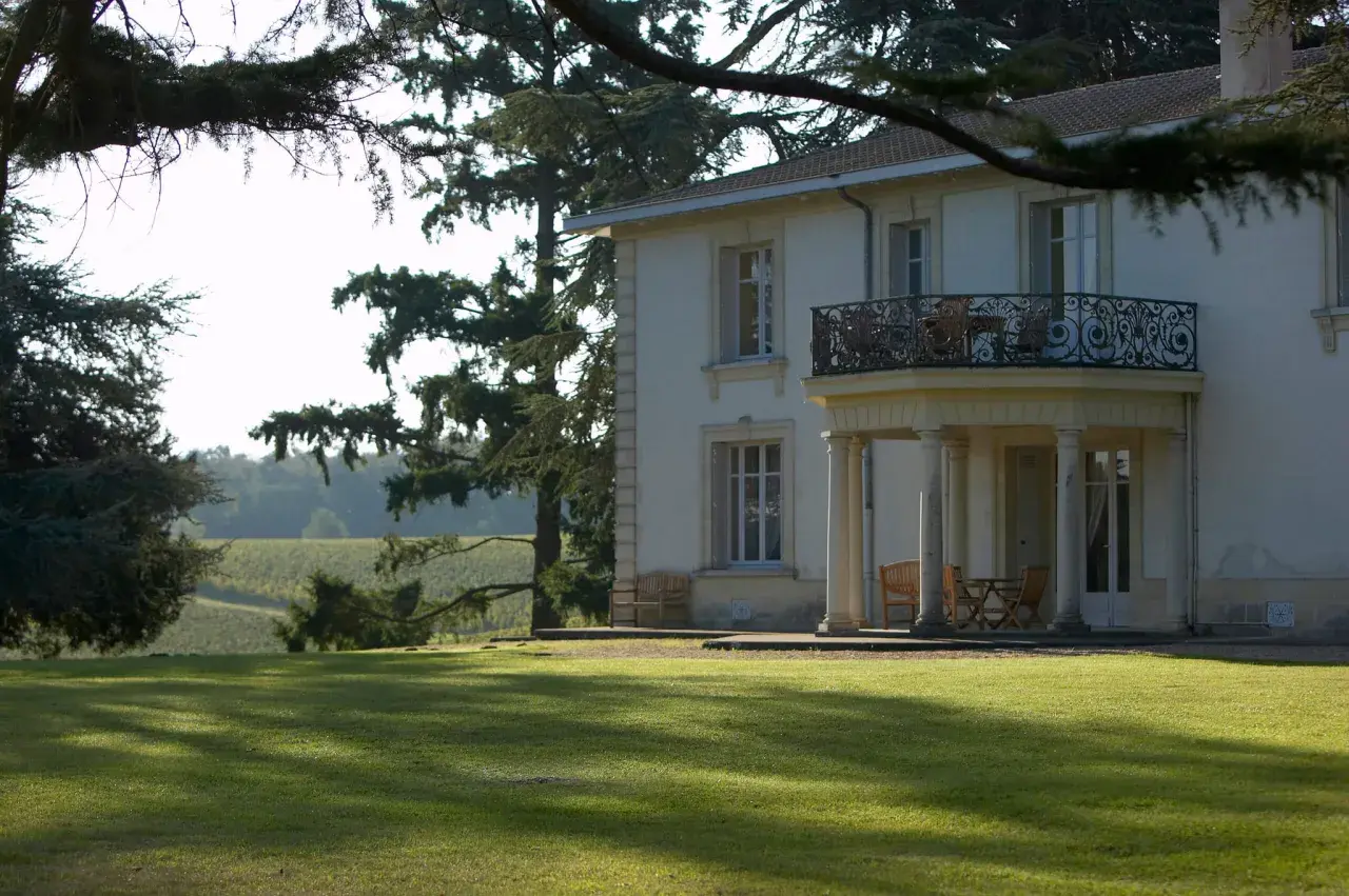 Le **château Pey la Tour** se dresse majestueusement, entouré de vignobles verdoyants sous un ciel clair. Une pelouse impeccable invite à la détente.