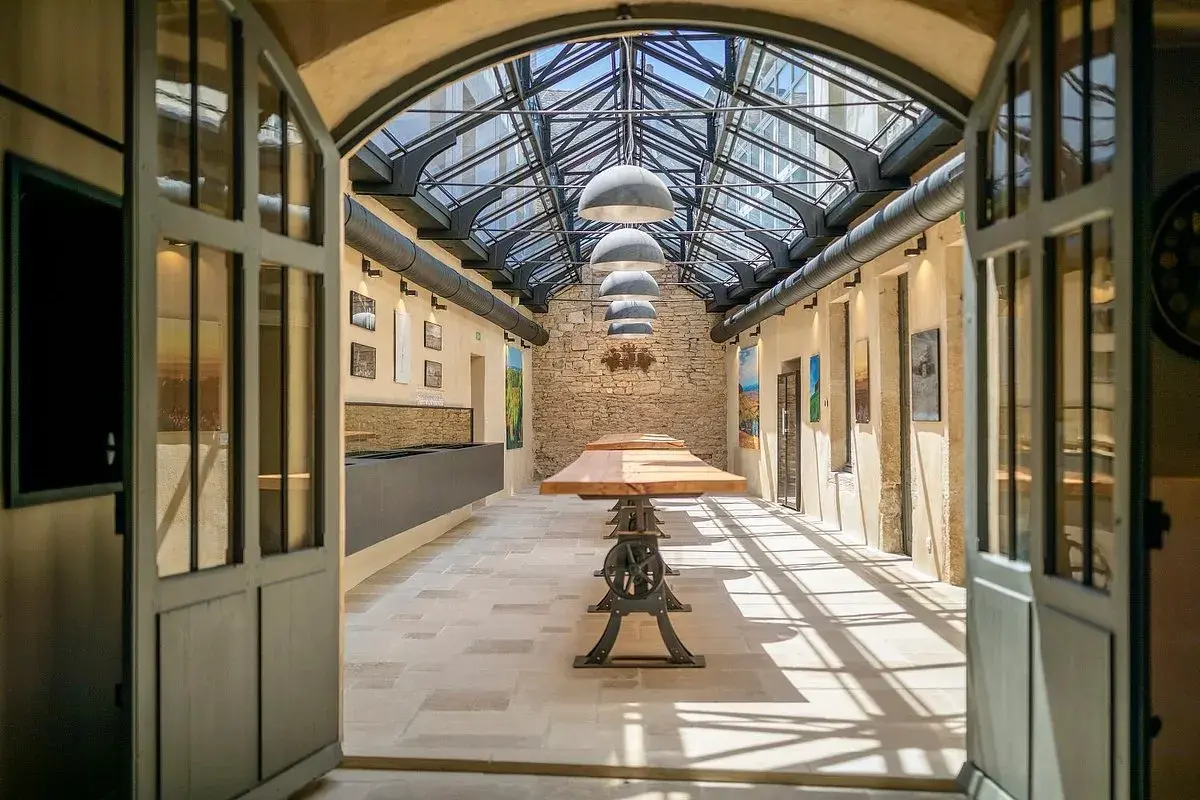 L'intérieur lumineux de la Maison Champy, avec son toit de verre, ses tables en bois et ses murs en pierre, invite à la dégustation.