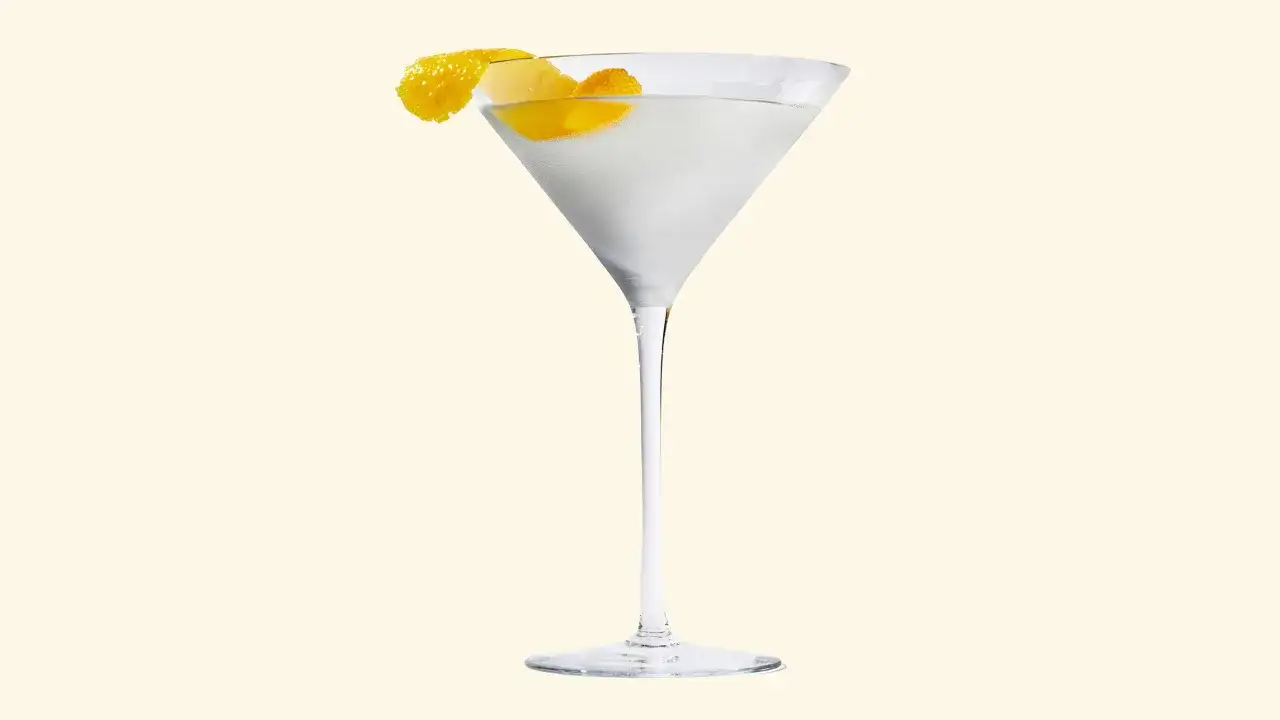 Un verre &agrave; cocktail rempli d'un liquide clair, garni d'un zeste de citron. La recette du dry martini est simple et &eacute;l&eacute;gante.