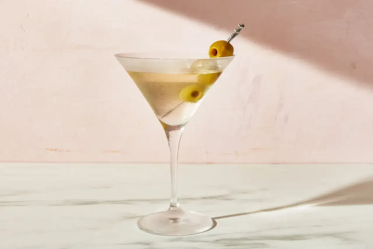 Un verre &agrave; martini rempli d'un cocktail clair, garni de deux olives sur une pique. Une invitation &agrave; d&eacute;couvrir la recette du dirty martini.