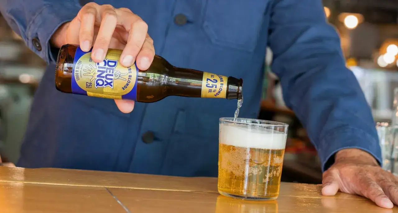 Une main verse une bi&egrave;re blonde l&eacute;g&egrave;re et dor&eacute;e, une bi&egrave;re peu alcoolis&eacute;e &agrave; 2.5% vol, dans un verre.