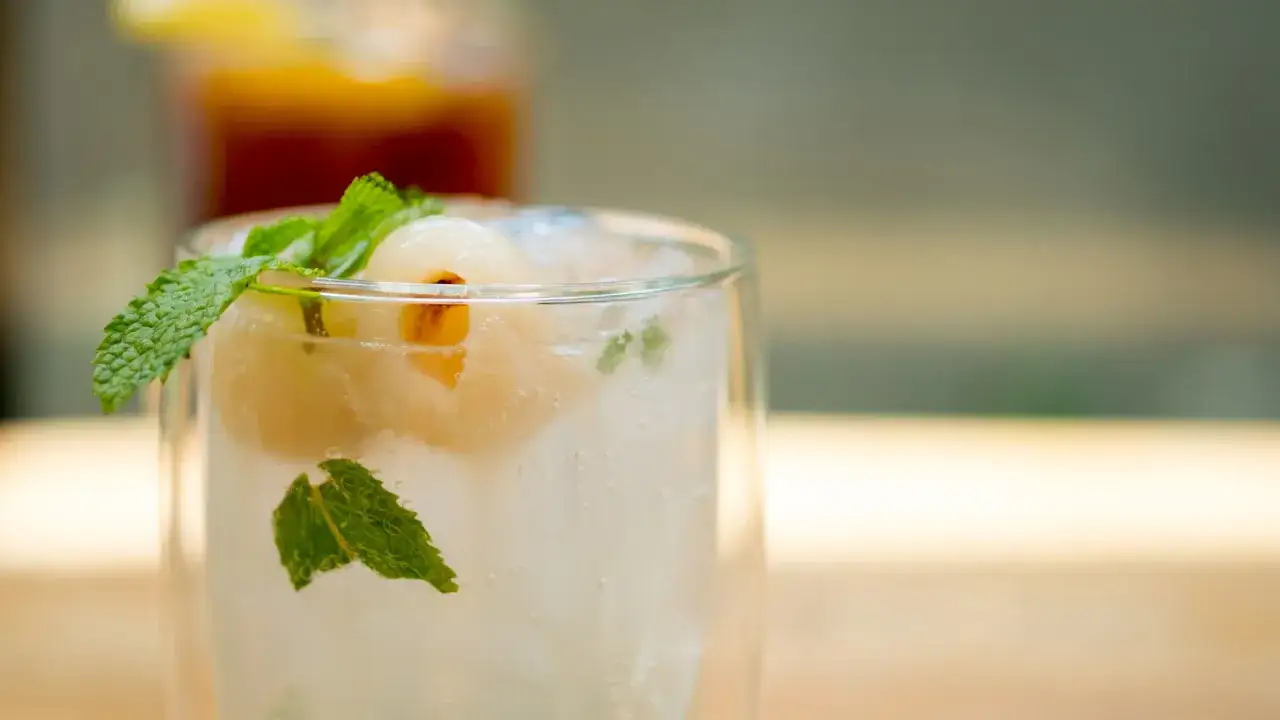Un verre de boisson p&eacute;tillante avec des litchis et de la menthe, offrant un &eacute;quilibre parfait entre le sweet and sour.