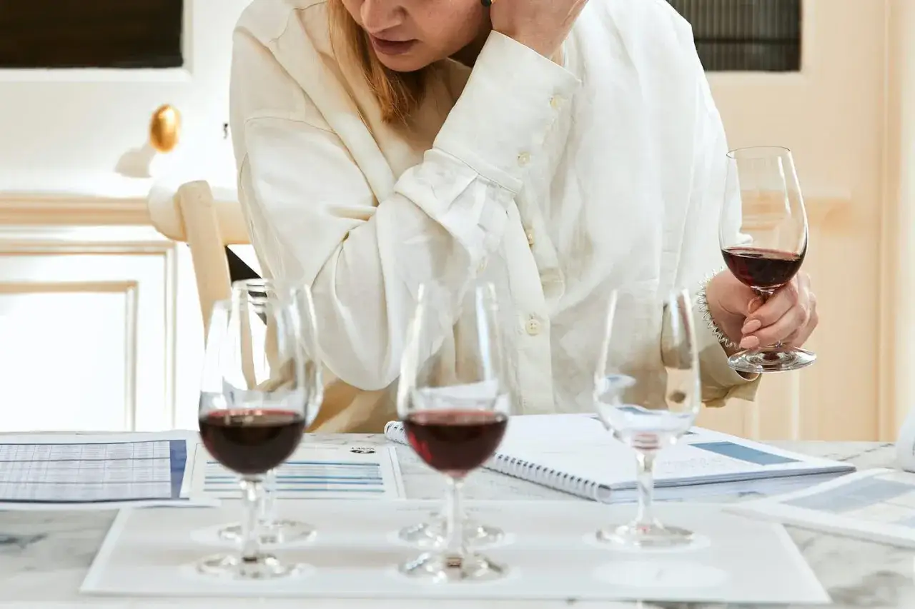 Une personne participe à une formation vin, dégustant un verre de vin rouge tout en consultant des notes.