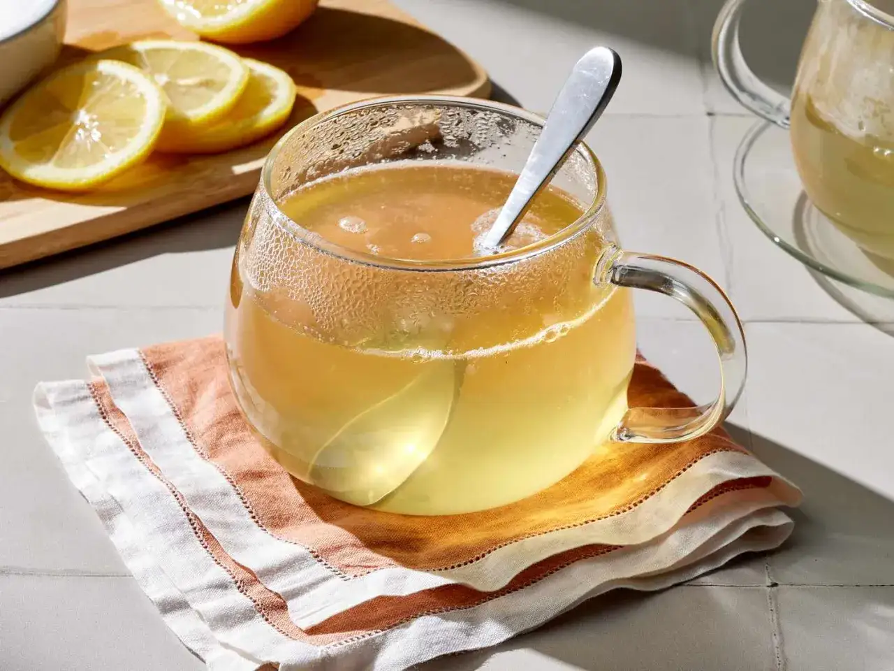 Une tasse de boisson eau et miel fumante, avec des rondelles de citron sur une planche &agrave; d&eacute;couper en arri&egrave;re-plan.