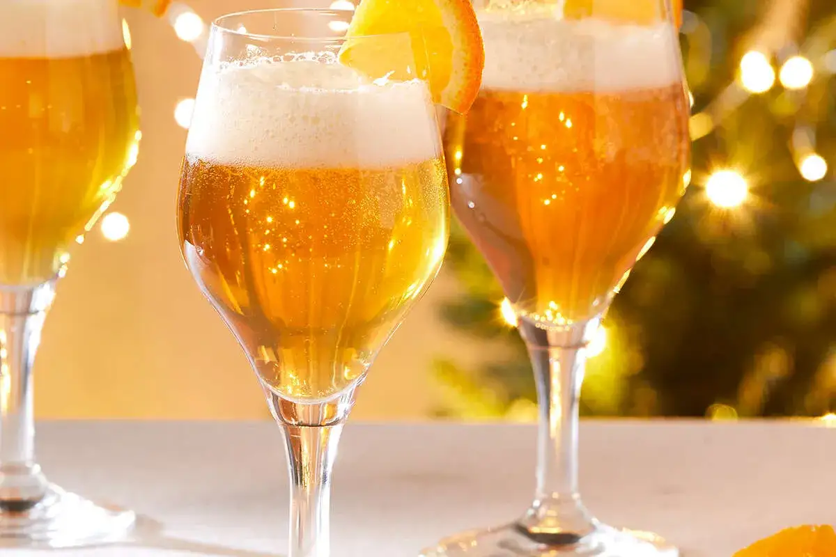Trois verres de bi&egrave;re dor&eacute;e, orn&eacute;s d'une tranche d'orange, scintillent sous les lumi&egrave;res festives. Une boisson qui, malgr&eacute; son allure festive, peut &ecirc;tre mauvaise pour la sant&eacute;.