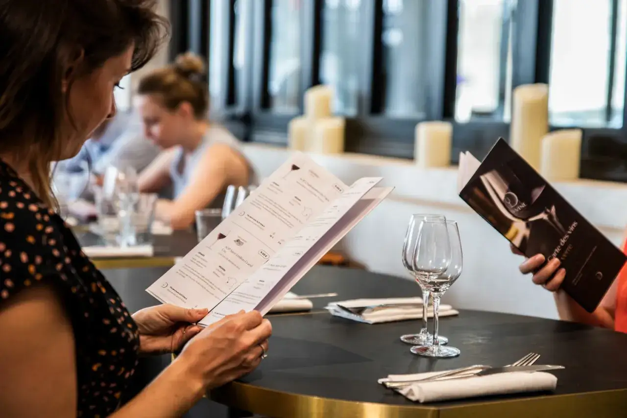 Une femme lit la carte des vins, choisissant la quantit&eacute; de vin parfaite pour son repas.