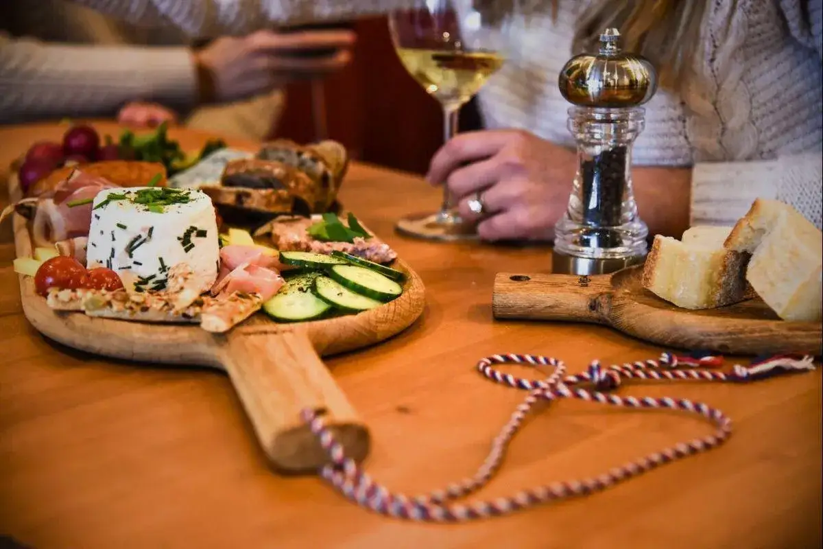 Un verre de vin blanc, une boisson pour ouvrir l'appétit, accompagne un plateau de fromages, charcuteries et crudités.