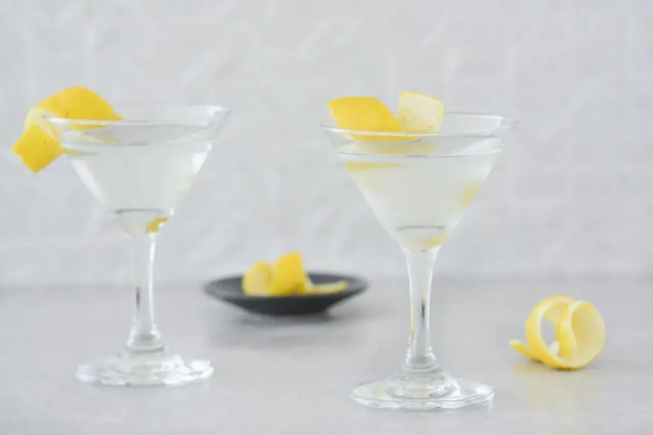 Deux cocktails gin martini glac&eacute;s, orn&eacute;s de zestes de citron, pr&ecirc;ts &agrave; &ecirc;tre d&eacute;gust&eacute;s.