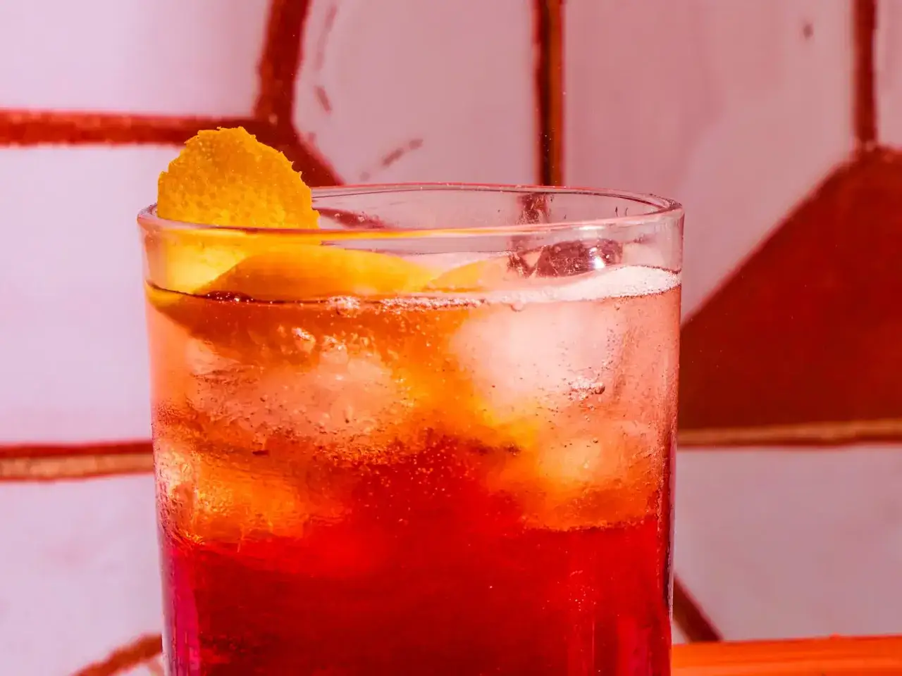 Un verre d'Americano traditionnel, rafraîchi par des glaçons et garni d'une écorce d'orange. Parfait pour une pause estivale.