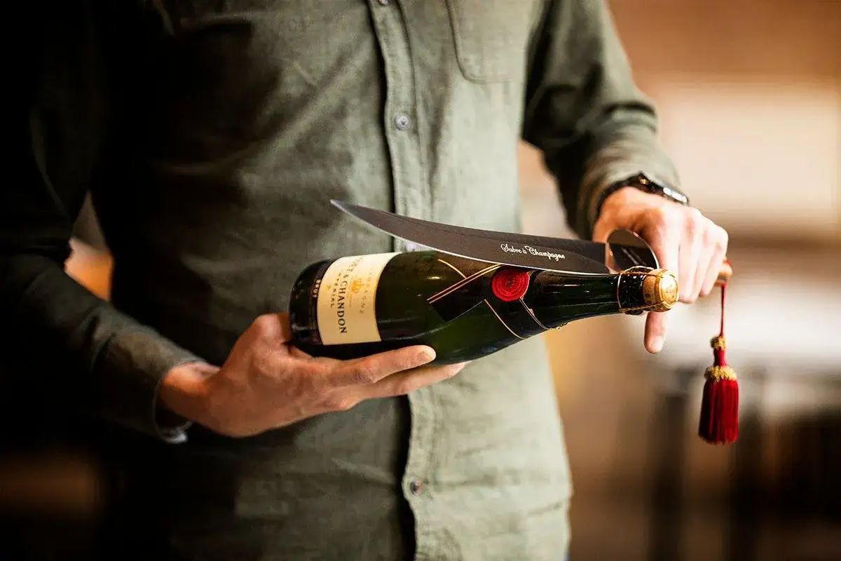 Un homme s'appr&ecirc;te &agrave; sabler le champagne, une tradition d'origine militaire pour ouvrir la bouteille avec un sabre.