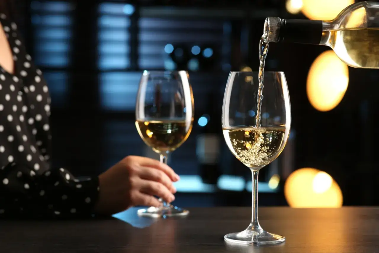 Vin blanc versé dans un verre, avec un autre verre déjà servi. On se demande combien de verre dans 1 litre de vin.